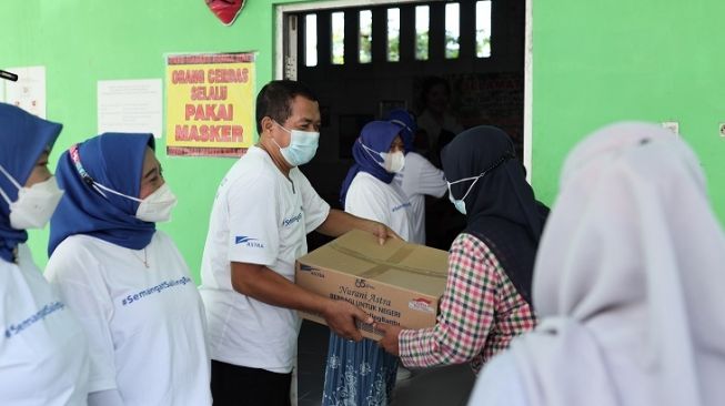 Warga Kampung Berseri Astra (KBA) Proklim Sunter Jaya, Jakarta Utara bahu-membahu dalam mendistribusikan paket bantuan #SemangatSalingBantu dari Astra bagi masyarakat yang membutuhkan [PT Astra International Tbk].