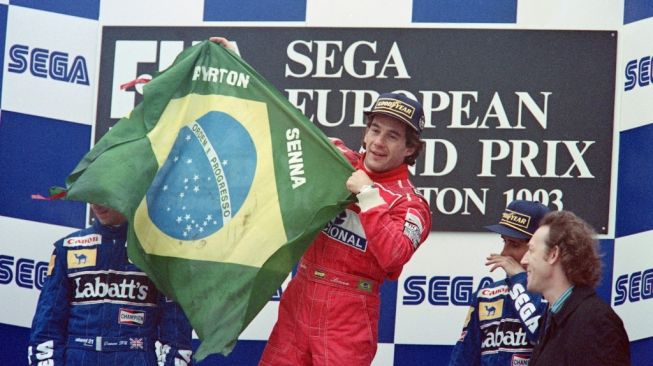 Pembalap Brasil Ayrton Senna mengibarkan bendera Brasil setelah memenangkan F1 GP Eropa di Donington Park, Britania Raya, dengan jet darat McLaren-Ford pada 11 April 1993. Pembalap Renault-Williams,  Damon Hill dan Alain Prost berada di urutan kedua dan ketiga [AFP/Pascal Pavani].